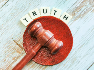 Phrase truth lettering created using square letter tiles with gavel isolated on dark background.