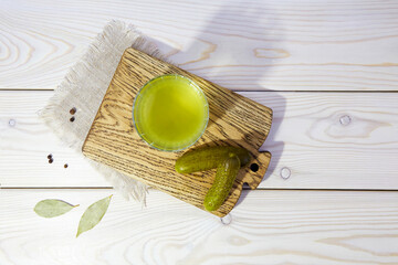 Pickle juice or cucumber pickle on a white wooden background. Healthy energy drink for athletes....