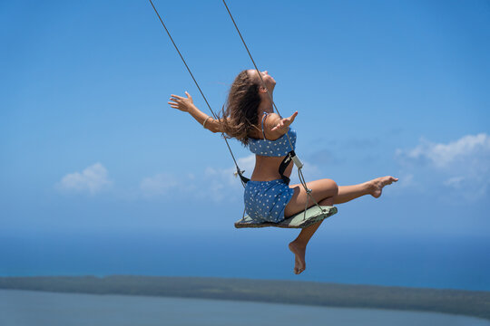 Young Beautiful Caucasian Woman On The Rope Swing With Sea And Sky Background. Concept Of Vacation And Travel 