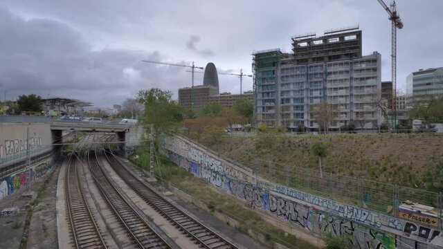 Trains passing on railroad near Marina neighborhood with Agbar Tower in background, Barcelona. Time-lapse