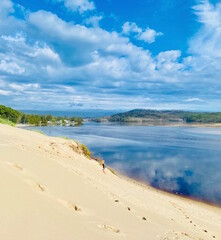 Child climbing up sand dune with lake in view