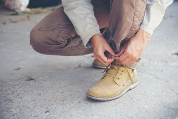 Man kneel down and tie shoes industry boots for worker. Close up shot of man hands tied shoestring...