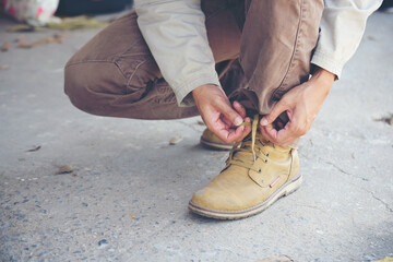 Man kneel down and tie shoes industry boots for worker. Close up shot of man hands tied shoestring...