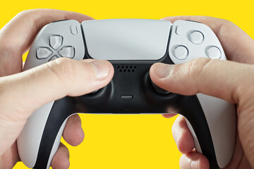 hand holding next generation joystick on yellow background - game controller.