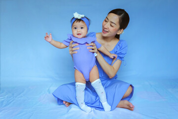 portrait baby and mom in violets dress in smile and happy emotional with blue background
