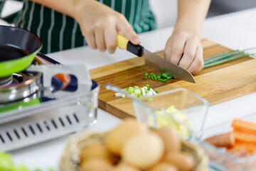 Obraz na płótnie Canvas Cropped photo of kid learn to cook healthy food for family in modern home kitchen by using knife slice food on wooden plate into pieces.