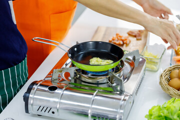 Steam vaporing out from raw material roasted on green flying pan on metal gas stove as starting of...