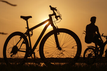 Obraz premium A silhouette of a bike at sunset. The sun shines through the bicycle frame, selective focus