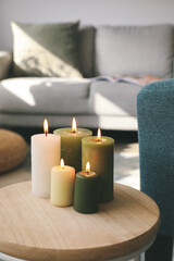 Fototapeta na wymiar Burning candles on table in stylish living room, closeup