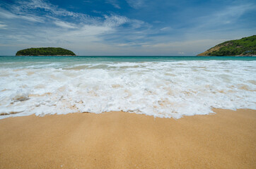 Sea wave foam on sandy beach, turquoise water, bright sunny day