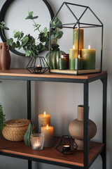 Beautiful burning candles on shelf in room
