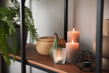 Beautiful burning candles on shelf in room, closeup