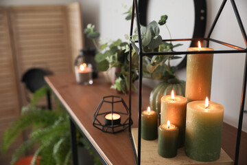 Beautiful burning candles on shelf in room, closeup