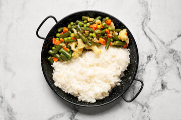 Frying pan with cooked vegetables and rice on white background