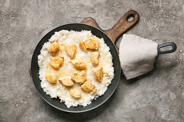 Frying pan with cooked chicken and rice on grunge background
