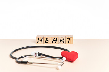 Word HEART made with cubes next to a stethoscope and a red heart