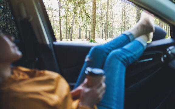 Closeup image of a woman laying and drinking coffee in the car