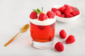 Glass of tasty raspberry jelly on light background