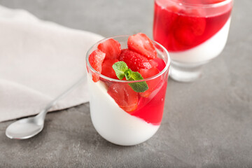 Glasses of tasty strawberry jelly on grey background