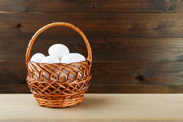 basket  of chicken eggs is on wooden background