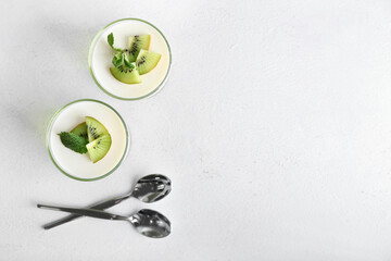 Glasses of tasty jelly with kiwi on light background