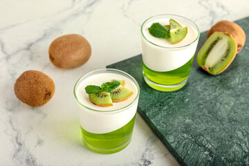 Glasses of tasty jelly with kiwi on light background