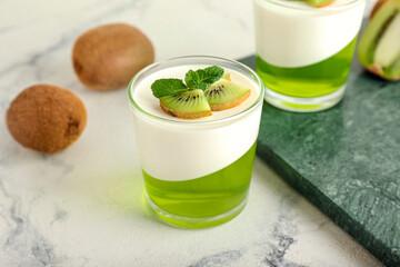 Glasses of tasty jelly with kiwi on light background