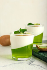 Glasses of tasty jelly with kiwi on light background