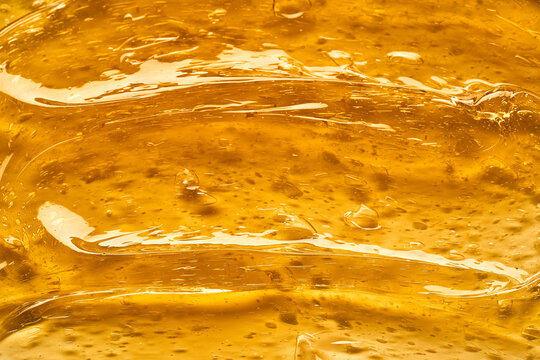 Transparent yellow smear of face cream or golden honey isolated on white background. Golden creamy texture on white background.