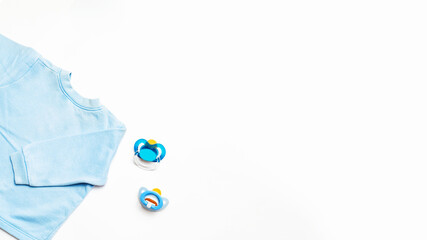 Top view of blue baby boy shirt and nipple on white table background. Mock up. Copy space. Kids accessories
