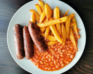 Grilled beef sausages with chips and baked beans. British classic food.