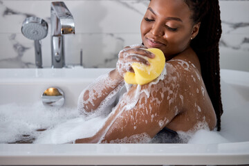 African Woman Washing Herself, Taking Bath With Sponge At Home, Free Space. Side View On Delighted...