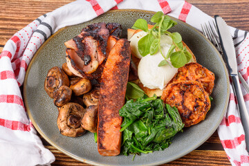 A serving of breakfast consisting of bacon, tomato, eggs, toast, mushrooms and spinach