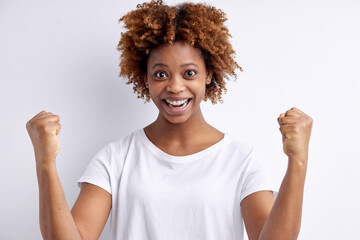 african american woman celebrating surprised and amazed for success with arms raised isolated over white studio background. black lady with curly hair looking happy