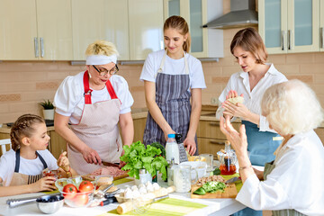 Positive diverse generation family women chopping ingredients for pizza, cooking, enjoying the process of preparing food together, have talk, teach and learn. dinner, holiday, weekend, family concept