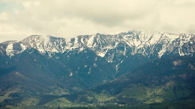 Heavy clouds over the Bucegi mountains in Romania during a spring day, as seen from the hills of Pestera village.