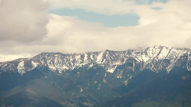 Timelapse with clouds over the Bucegi mountains in Romania during a spring day, as seen from the hills of Pestera village.