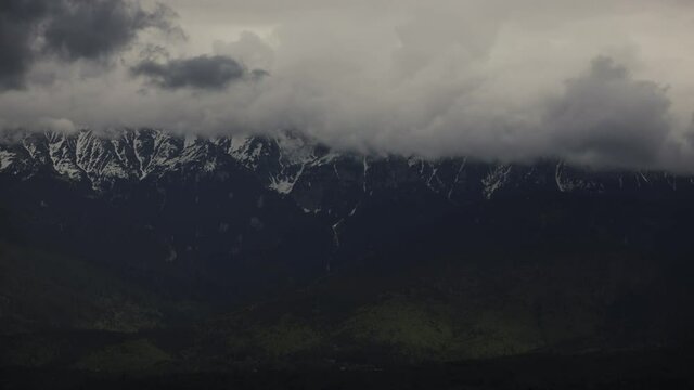 Timelapse with clouds over the Bucegi mountains in Romania during a spring day, as seen from the hills of Pestera village.