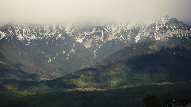Heavy clouds over the Bucegi mountains in Romania during a spring day, as seen from the hills of Pestera village.
