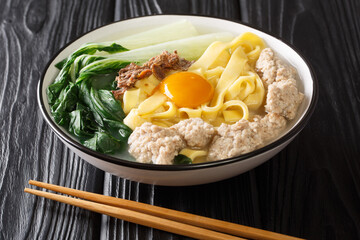 Singapore style homemade noodle soup with fried anchovies, meatballs, egg and bok choy close-up in a bowl on the table. horizontal
