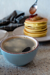 pancakes with strawberry jam and a cup of coffee
