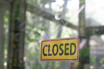 Closed signboard hanging on glass door of a restaurant. Business shuttered during pandemic concept.
