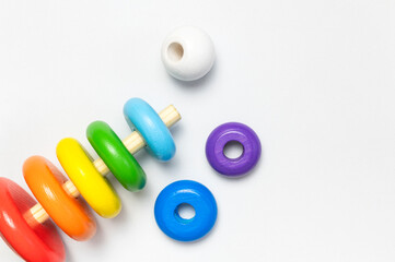 Multi-colored wooden children's toy pyramid on white background. Eco friendly toy, plastic free. Toy for babies and toddlers. Natural wood toys. Colors of rainbow. Flat lay top view copy space