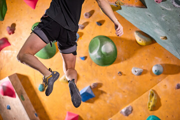 adult man in sportswear climbing rock wall indoor. Concept of sport life. Professional athlete enjoy climbing, doesn't afraid of height. rock climbing, bouldering, workout concept. male hung in air