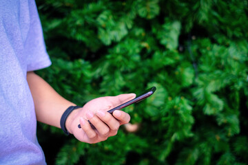 Man holding smartphone with christmas tree background, Technology concept.