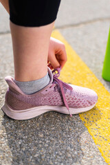 Naklejka premium Young woman tying her shoelaces at outdoors training