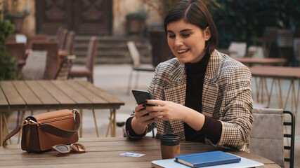 Attractive cheerful entrepreneur looking happy texting on smartp