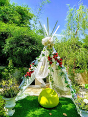 A teepee style tent covered in flowers in a tropical garden as a romantic decorative feature for people to relax in, blue sky background © Hi-Point