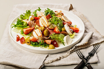 Close-up of an appetizing salad with strawberries, grapes, mozzarella and olives with pomegranate sauce. Vegetarian meals. Healthy and balanced nutrition. Organic food. Mediterranean cuisine recipes