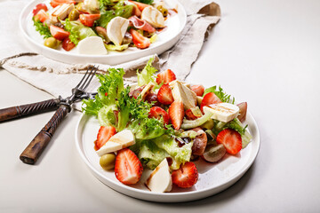 Tasty salad with jamon, strawberries, grapes, mozzarella and olives with pomegranate sauce. Healthy and balanced nutrition. Organic food. Mediterranean cuisine recipes. Copy space